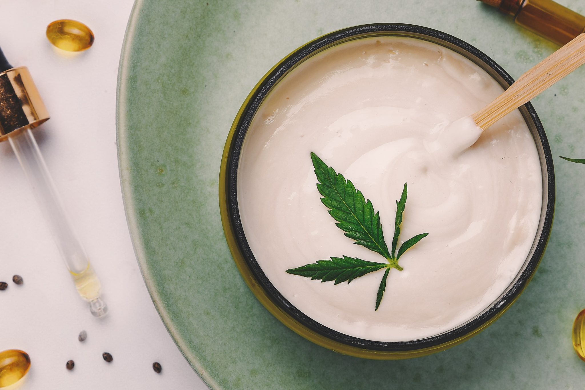 Pot de lotion blanche au chanvre. Crème de cannabis avec feuille de marijuana - concept de cannabis. Mise à plat, vue de dessus.