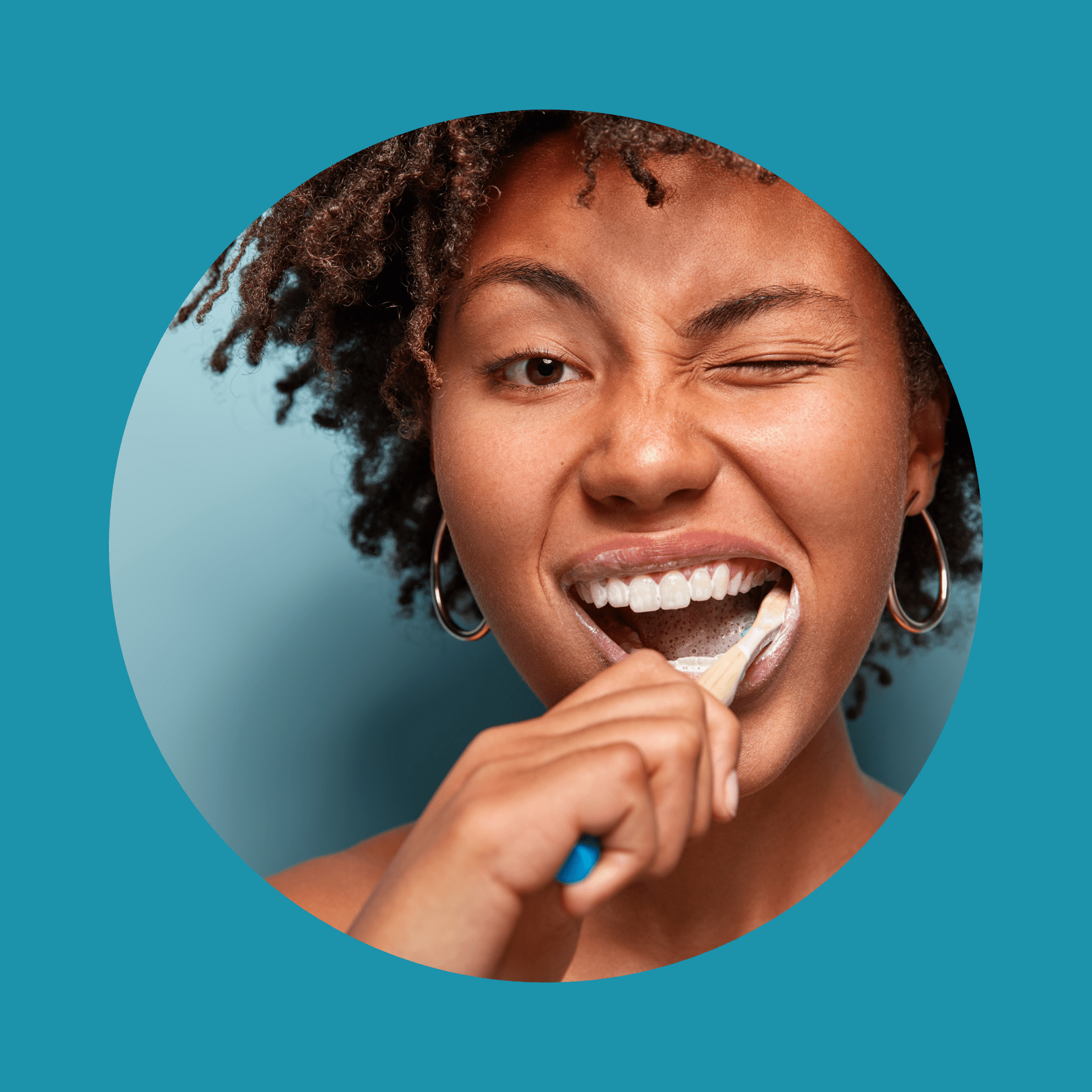 Tooth care concept. Slim naked young woman blinks eye, has daily routine after shower, brushes teeth with tootbrush, has healthy skin, isolated over blue background, free space for your promotion.
